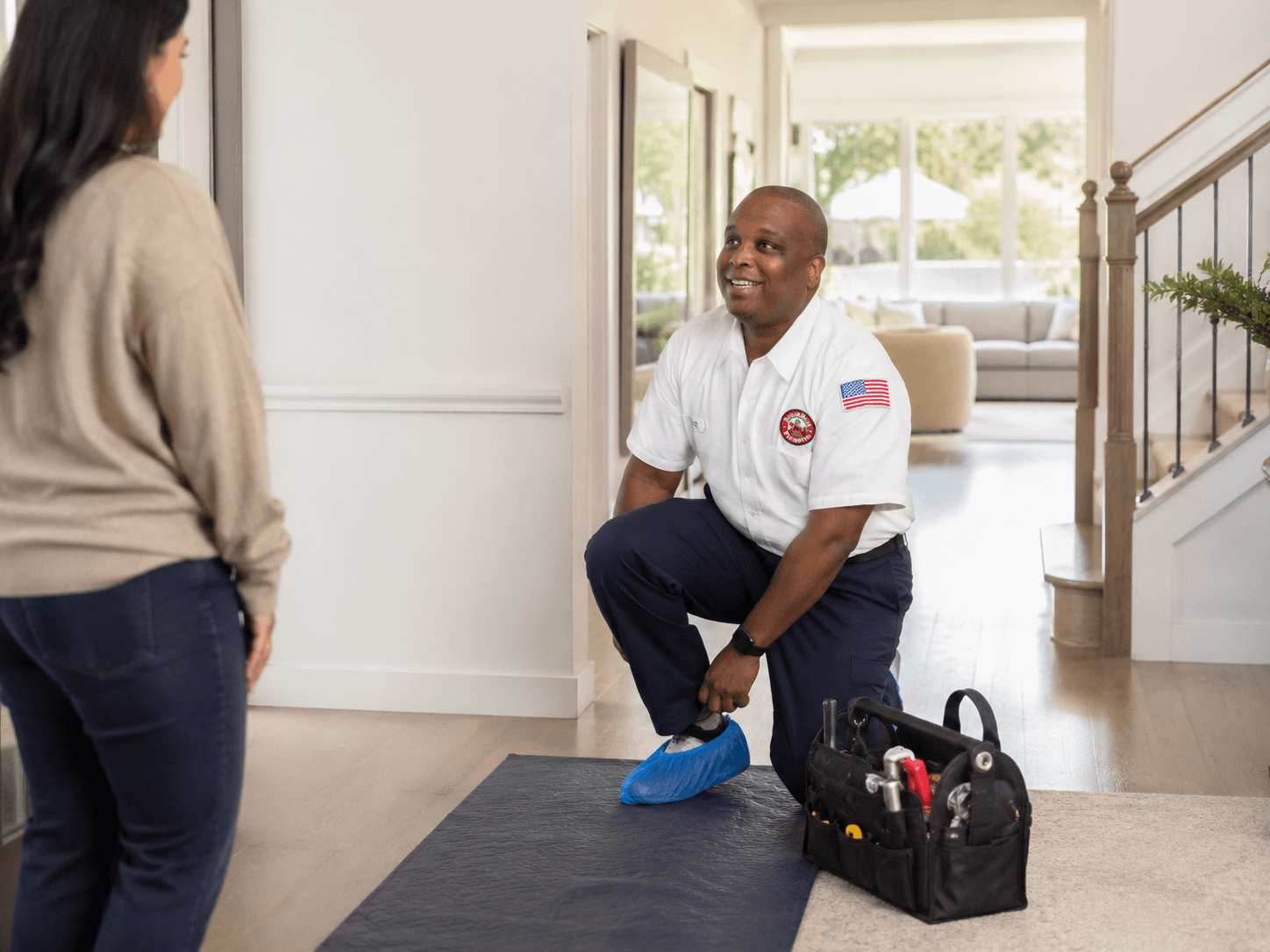 Sugar Bear technician putting on shoe covers on a floor protection mat
