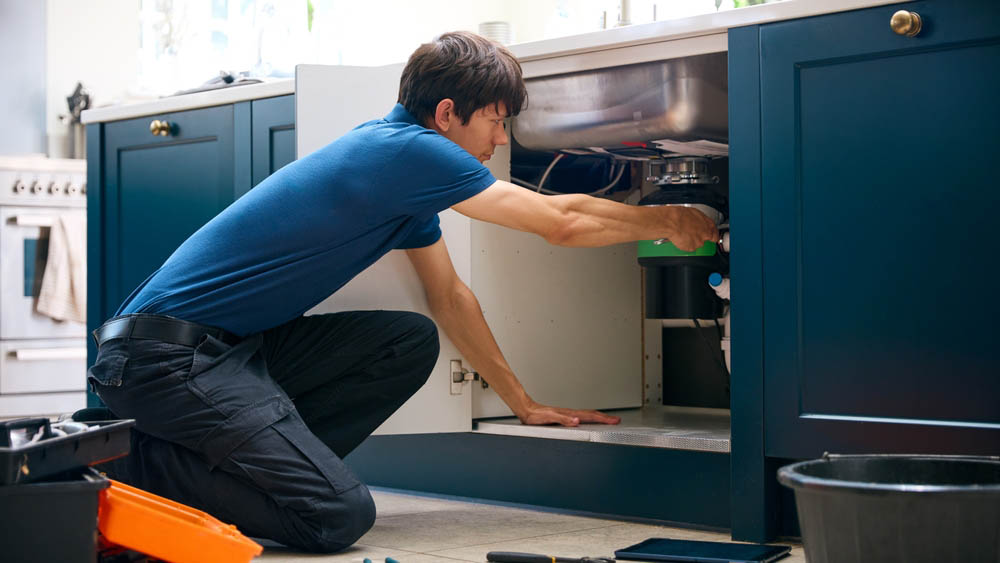 Sugar Bear technician installing a garbage disposal unit Sugar Bear technician installing a garbage disposal unit