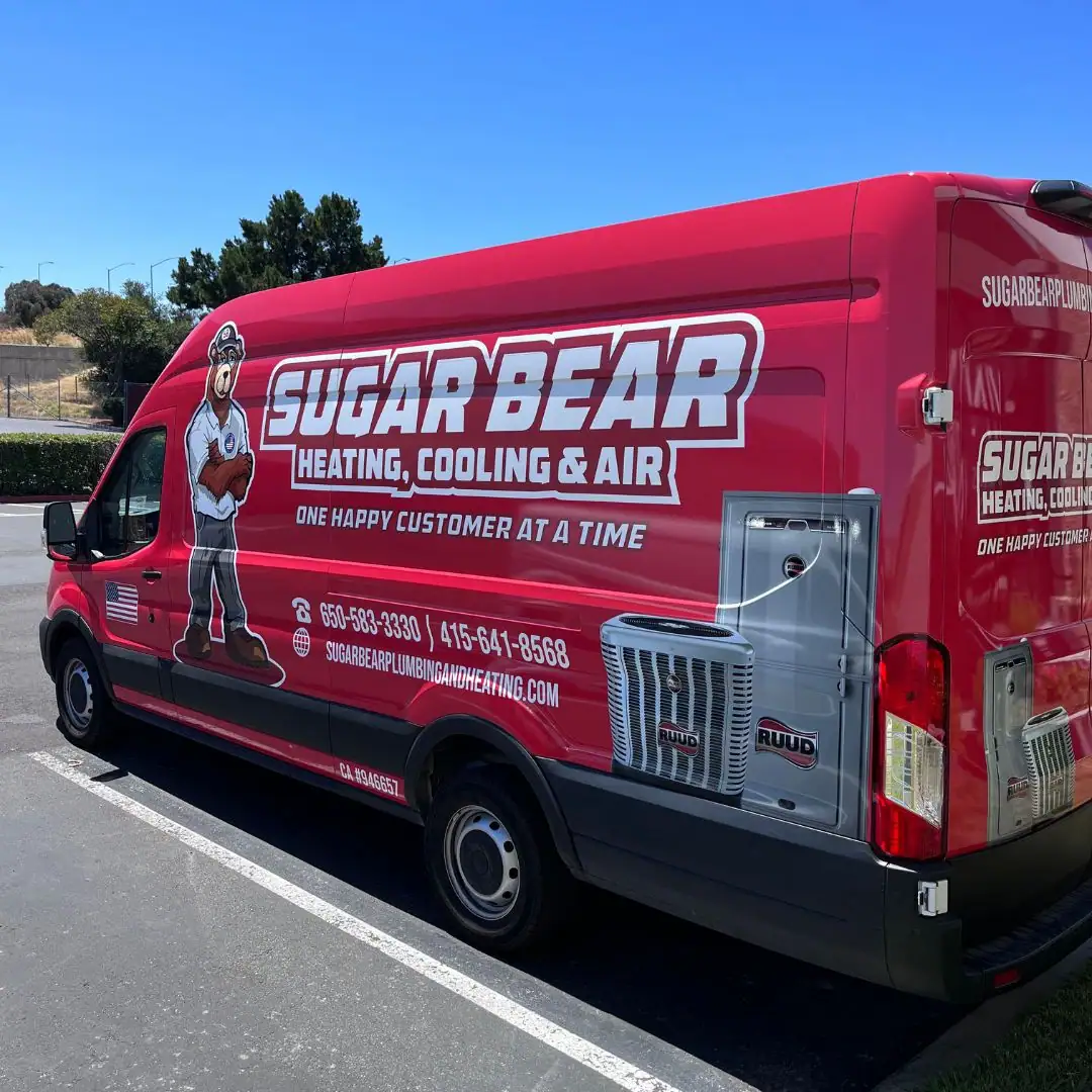 A red Sugar Bear Heating, Cooling & Air service van is parked in a lot. The van has a cartoon bear mascot and company contact details printed on its side.