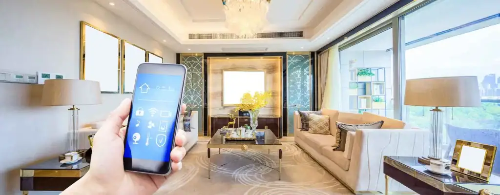 A hand holds a smartphone displaying smart home controls in a bright, modern living room with elegant furniture, large windows, and contemporary decor.